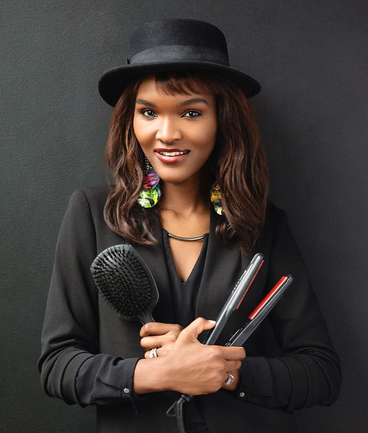 Karen Spicer is a hairstylist holding a hairbrush and flat iron
